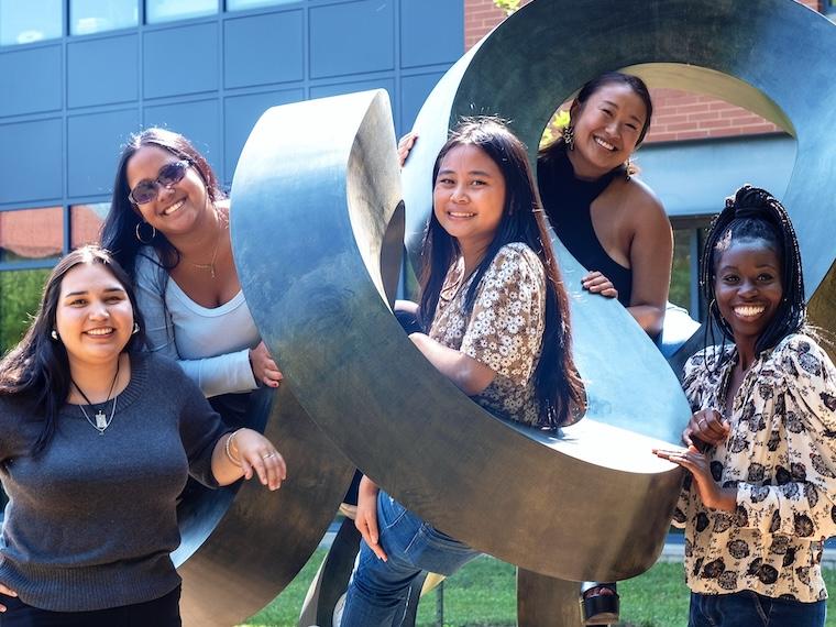 Student researchers pose by sculpture.