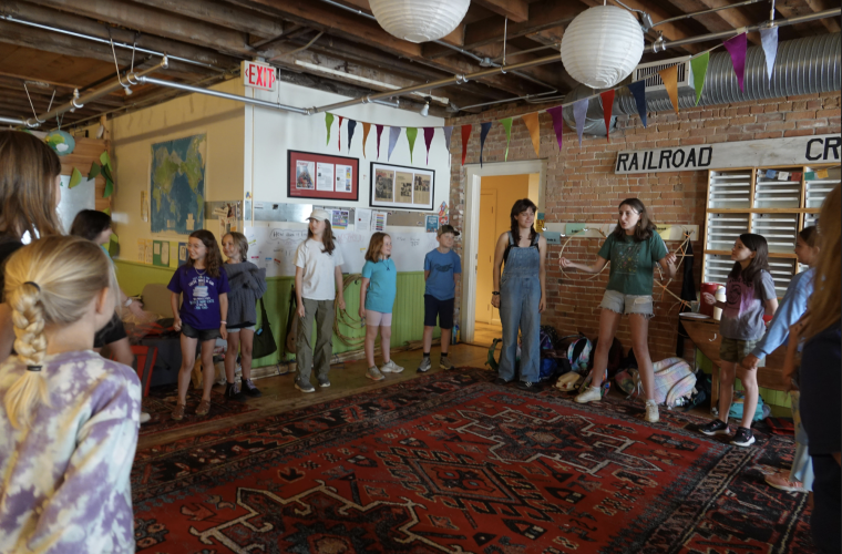 College interns and younger children stand in a circle