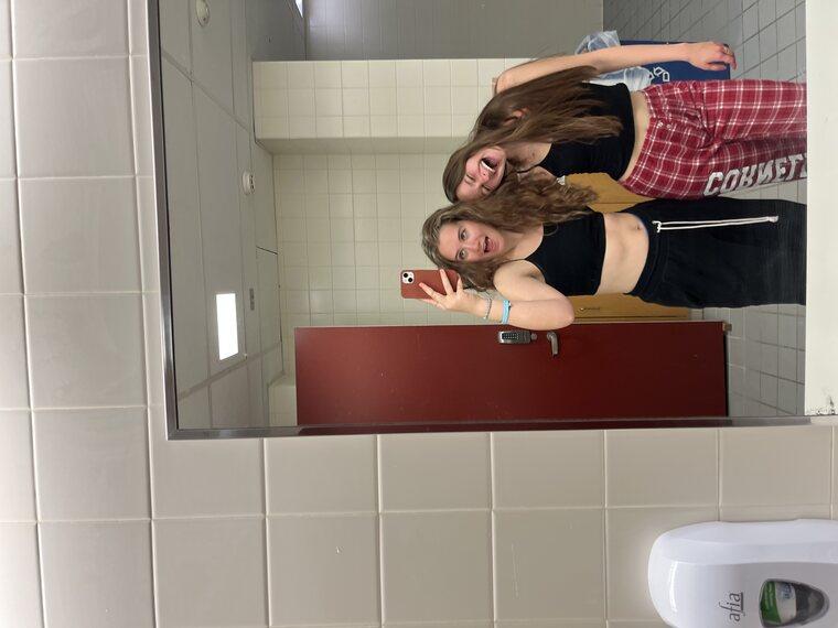 Two girls posed in a bathroom mirror